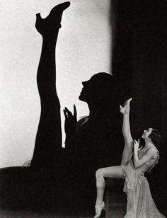 a black and white photo of a woman in front of a man's shadow