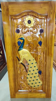 an intricately carved wooden panel with a peacock on it's back and yellow feathers