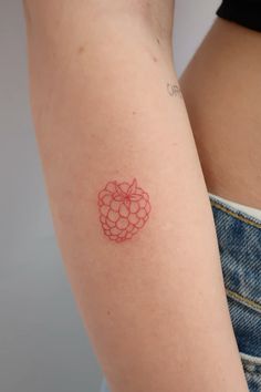 a woman's arm with a small red tattoo on the left side of her arm