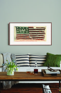 a living room with a couch, coffee table and framed american flag on the wall