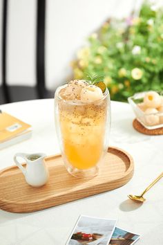 a glass filled with liquid sitting on top of a wooden tray