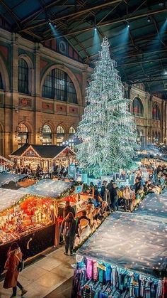 a christmas tree is lit up in the middle of an indoor market