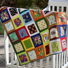 a multicolored patchwork quilt on a white bench