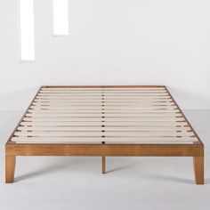 a bed frame with wooden slats and white sheets