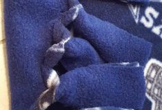 two blue towels folded on top of each other next to a tile floor and wall