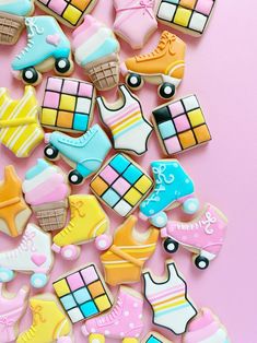 colorful decorated cookies are arranged on a pink surface with one cookie in the shape of a roller skate