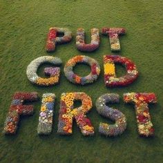 the words put god first are made out of flowers on the grass in front of a field