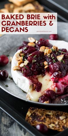 baked brie with cranberries and pecans on a plate next to crackers