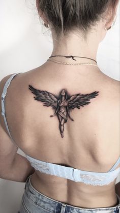 a woman with a cross tattoo on her upper back shoulder and behind her is an angel