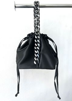 Our smooth satin drawstring bag gathers at the top from a square structured base, and is handled by gun metal hardware that creates and elegant yet fierce pouch bag. Satin shell, satin lining, gun metal hardware. Polyester 100%. Drawstring closure. 6"x 6" base Made in USA. One Size. Need help with sizing? Size Guide Elegant Evening Bucket Bag With Silver-tone Hardware, Chic Party Bucket Bag With Silver-tone Hardware, Elegant Pouch Bucket Bag With Silver-tone Hardware, Modern Bucket Bag With Removable Pouch For Party, Elegant Evening Pouch Bucket Bag, Elegant Evening Bucket Bag In Pouch Style, Elegant Evening Bucket Bag Pouch, Elegant Silver Bucket Bag For Evening, Modern Bucket Bag With Chain Strap For Evening