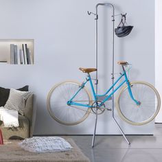 a blue bike is hanging from a metal rack in front of a white wall with an advertisement on it