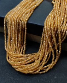 a close up of a gold necklace on a black surface with a book in the background