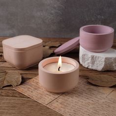 a candle sitting on top of a wooden table next to a container with a lid