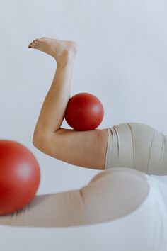 a woman with her arms and legs stretched out holding two red balls