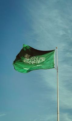 a green flag flying in the sky with arabic writing on it's back side