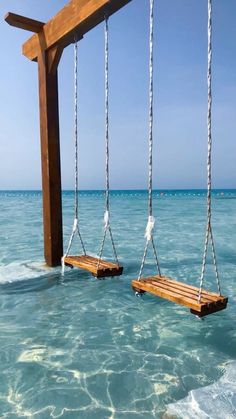 two wooden swings suspended in the ocean water