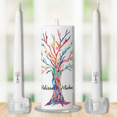 a candle with a tree on it next to two candles