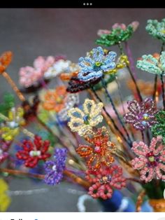 there are many colorful flowers in the vase on the table and one is made out of beads