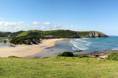 the beach is surrounded by lush green hills