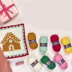 crochet and knitting supplies are laid out on a white surface next to a pink gift box