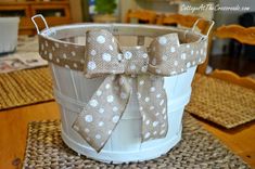 a white bucket sitting on top of a wooden table with a bow tie around it