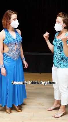 two women in blue dresses and masks standing on a stage with one woman wearing a face mask