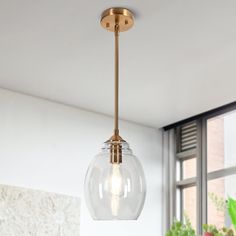 a light fixture hanging from the ceiling in a room with windows and potted plants