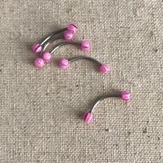 two pink and silver hair pins laying on the ground next to each other with holes in them