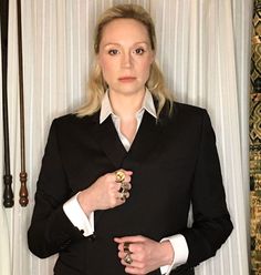 a woman in a black suit and white shirt is standing with her hands on her hips