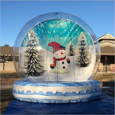 an inflatable snow globe with a snowman on it and trees behind it