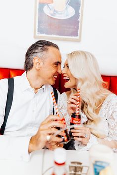 a man and woman sitting next to each other at a table with drinks in front of them