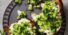 two pieces of bread with cucumbers and cream cheese on them, sitting on a plate