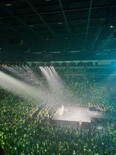 a large group of people standing around a stage spraying water on them with their hands