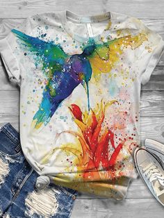 a t - shirt with a colorful hummingbird on it, next to ripped jeans