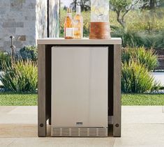 a stainless steel outdoor cooler with bottles on top