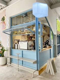 a blue and white building with a bench in front of it on the ground next to potted plants