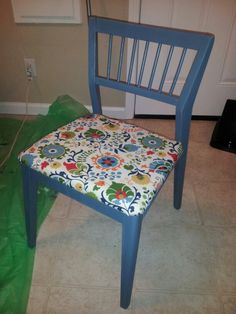 a blue chair sitting on top of a tile floor next to a green bag and a white door