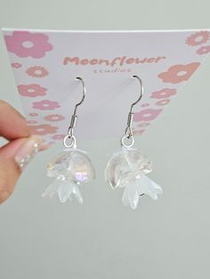 These cute jellyfish earrings are a delightful and whimsical accessory that add a touch of playful charm to any outfit. These earrings are crafted from high-quality materials such as sterling silver, gold-plated metal, or acrylic, and feature intricate detailing to resemble the graceful and otherworldly beauty of jellyfish. Drop Length: 3 inches material: sterling silver, jelly head (acrylic) Quantity: 2 pieces / 1 pair DISCLAIMER: Handcrafted Nature: Handmade jewelry is crafted by me and may ha Cute Clear Dangle Earrings, White Earrings With Dangling Charms For Gift, Whimsical White Drop Earrings, Whimsical Silver Dangle Flower Earrings, Whimsical Silver Flower Earrings, Jellyfish Earrings, Otherworldly Beauty, Cute Jellyfish, Moon Jellyfish