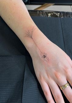 a woman's hand with a spider web tattoo on her left arm and wrist