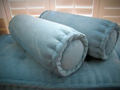 two pillows are folded on top of each other in the shape of a rolled up blanket