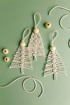 three small christmas trees made out of yarn and wood beads on a green background with twine