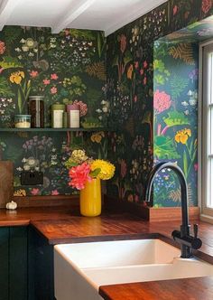 a kitchen with floral wallpaper and wooden counter tops, along with a white sink