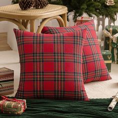 two red plaid pillows sitting on top of a bed next to a christmas tree and presents