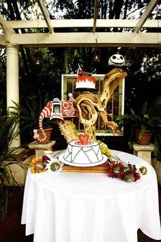 a white table topped with a cake covered in icing and candy canes next to potted plants