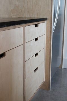 an unfinished kitchen cabinet with drawers and a refrigerator in the backgroung area