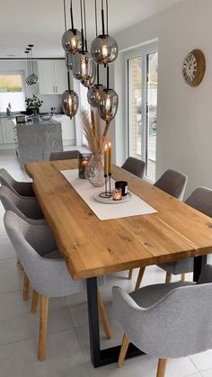 a dining room table and chairs with candles on it in front of a large window