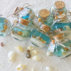 several small glass jars filled with sea shells and seashells on a lace tablecloth