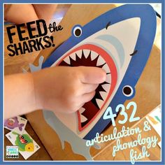 a young child is playing with a shark shaped cardboard box that says feed the sharks