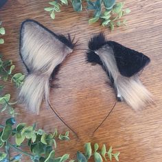 two black and white hair clips on top of a wooden table next to green plants