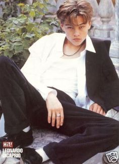 a young man sitting on top of a bench wearing black pants and a white shirt